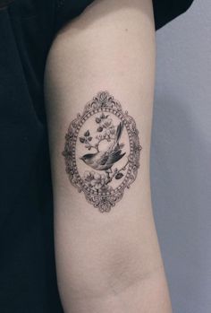 a small tattoo on the arm of a woman with a bird and flowers around it