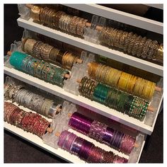 several rows of bracelets and bangles are on display in a case with clear drawers