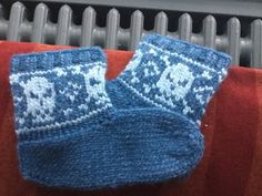 two blue knitted mittens sitting on top of a red blanket next to a radiator