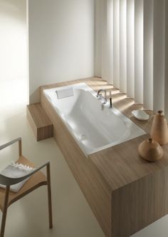 a bathtub sitting on top of a wooden counter next to a chair and window