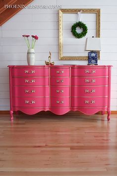 a pink dresser with gold trim and flowers on it in front of a stair case