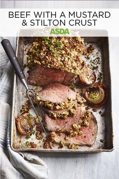 beef with mustard and stilton crust on a baking sheet next to an onion wedge