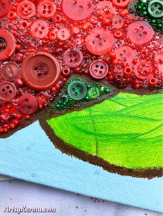 an art project with buttons and watercolors on paper, depicting a green tree