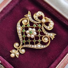 A stunning Edwardian pendant featuring demantoid garnets and seed pearls in a latticed body, with bow and leaf motifs, crafted in 15ct yellow gold, with a brooch and a pendant loop to the reverse. Circa 1900-1910. Stamped and tested as 15ct gold. The pendant measures approximately 41.5mm (L) x 27.9mm (W). The approximate weight is 6.3 grams. Please note that the chain and antique box pictured are for display purposes only. Thank you. CONDITION: In very good antique condition with some light surf Antique Green Brooches For Wedding, Ornate Green Brooches For Wedding, Art Deco Pendant Brooches As Gifts, Green Art Deco Brooches For Wedding, Art Deco Green Brooches For Wedding, Green Art Nouveau Wedding Brooches, Green Filigree Brooches As A Gift, Green Filigree Brooches As Gift, Green Filigree Brooches For Gifts