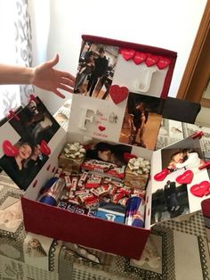 an open box filled with pictures and hearts on top of a table next to a person's hand