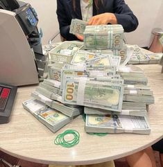 a woman is sitting at a table with stacks of money in front of her computer