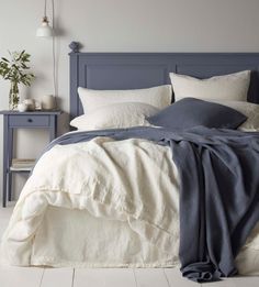 a bed with white and blue linens on top of it next to a night stand