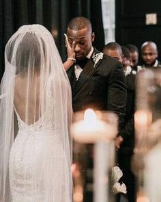 a man and woman standing next to each other in front of candles