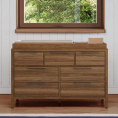 a large wooden dresser in front of a window with a view of the trees outside