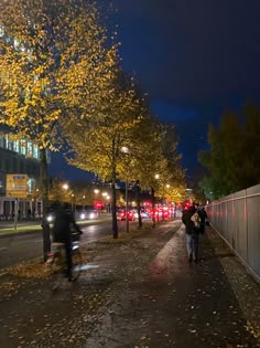 people walking down the street at night with their bikes parked on the side of the road