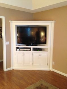 a flat screen tv sitting on top of a white entertainment center in a living room