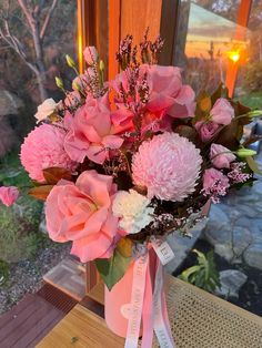 a vase filled with pink flowers sitting on top of a table next to a window