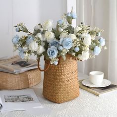 a wicker basket with blue and white flowers sitting on a table next to books