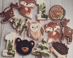 decorated cookies are arranged in the shape of animals and trees on a white wooden surface