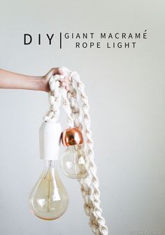 a person is holding a light bulb made out of rope and beads, which are hanging from the ceiling