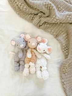 three crocheted stuffed animals laying on top of a blanket