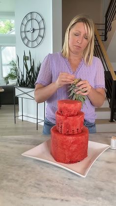 a woman standing in front of a red cake