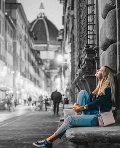 a woman sitting on a stone bench in the middle of a street with her eyes closed