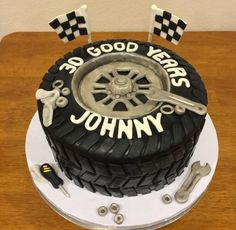 a birthday cake made to look like a tire with wrenches and flags on top