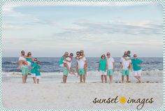 a group of people standing on top of a sandy beach next to the ocean with their arms around each other