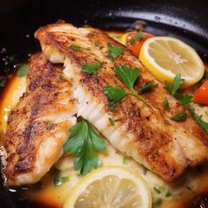 two fish fillets with lemon, carrots and parsley in a skillet