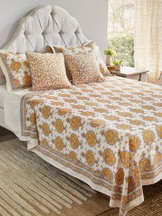 a bedroom with a bed covered in yellow and white sheets, pillows and rugs