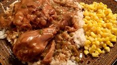 a plate with meat, rice and corn on the side is ready to be eaten