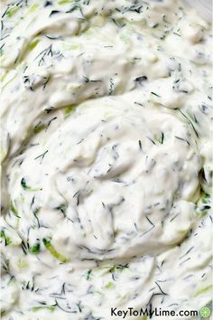 a white bowl filled with cream cheese and dill sprinkled on top of it