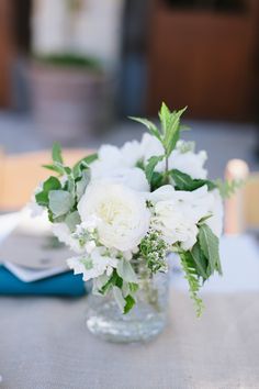 a vase filled with white flowers sitting on top of a table next to a book