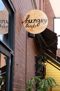 the sign for hungry birds is hanging on the side of the building next to some plants