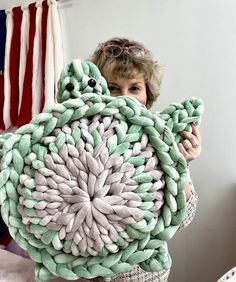 a woman holding up a large knitted object