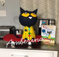 a black cat statue sitting on top of a counter next to a red skateboard