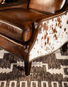 a brown and white leather chair sitting on top of a carpeted floor next to a rug