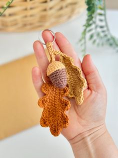 a hand holding a crocheted acorn and an acorn keychain