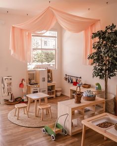 a child's playroom with wooden furniture and pink drapes over the windows