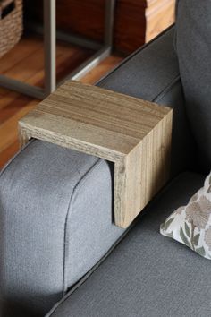 a small wooden table sitting on top of a gray couch next to a white pillow