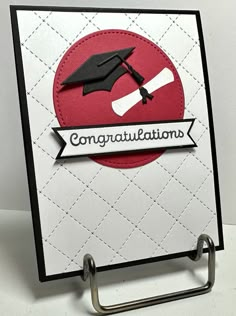 congratulations card with a graduation cap and diploma on the front, hanging from a metal holder