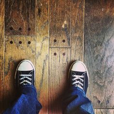 a person standing on top of a wooden floor next to a pair of blue jeans