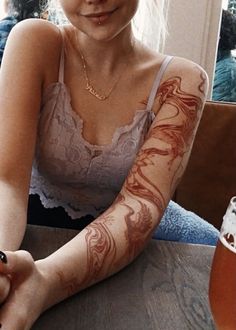 a woman sitting at a table with tattoos on her arm