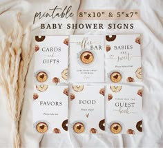 four baby shower signs are laid out on a bed with some dried grass next to them