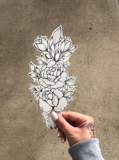 a person holding up a sticker with flowers on it in front of a concrete floor