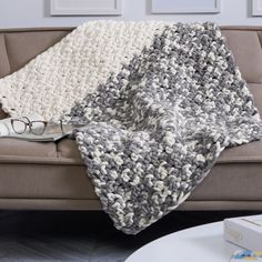 a gray and white blanket sitting on top of a couch next to a coffee table