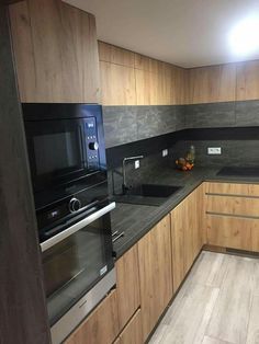 an empty kitchen with wooden cabinets and black counter tops, including a microwave oven on the wall