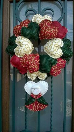 a wreath is hanging on the front door with red, white and green fabric flowers