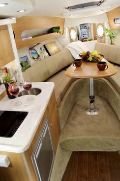 the inside of an airplane with wood flooring and white counter tops, two wine glasses on a round wooden table