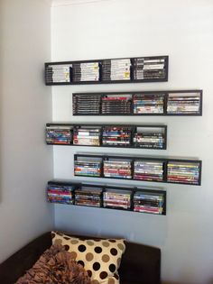 there is a wall mounted shelf with many video games on it and a couch in front of it