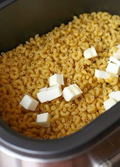 macaroni and cheese is being cooked in the crock pot with butter on top