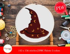 a cross stitch wizard hat with stars and moon on it, surrounded by sewing supplies