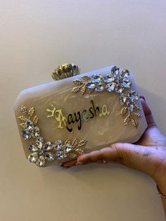 a hand holding a purse with the word ayesha written on it in gold and diamonds