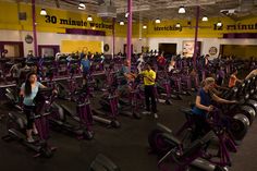 people are exercising on exercise bikes in a gym with yellow and purple walls behind them